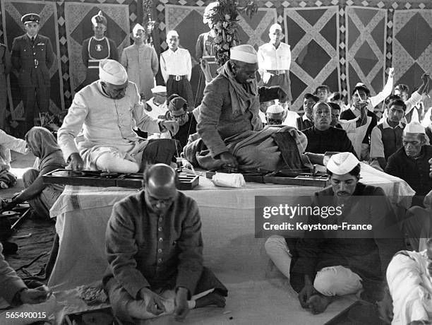 Le Premier ministre Jawaharlal Nehru et le Président de l'Inde Rajendra Prasad assis sur une estrade en train de filer du coton, entourés d'autres...