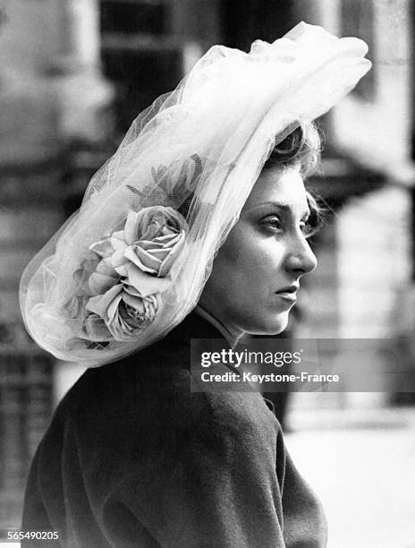 Elégante apercue au pesage avec un joli chapeau en tulle bleu orné de roses, à Paris, France, le 11 avril 1948.