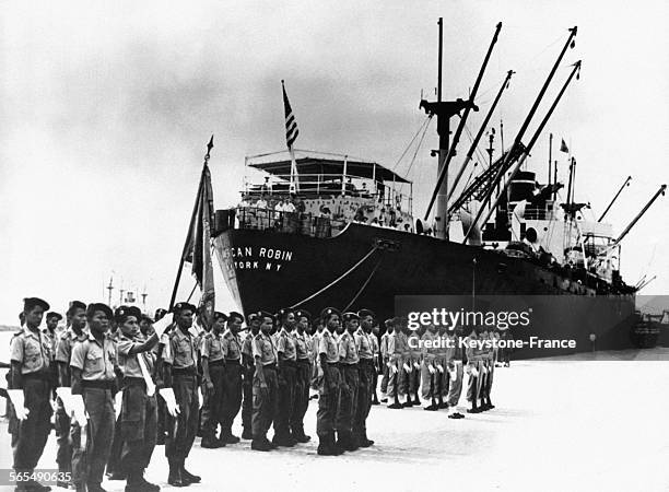 Accosté au quai du port de Saigon, au Viêt Nam, le bateau 'American Robin' est accueilli par une garde d'honneur représentant les trois états alliés...