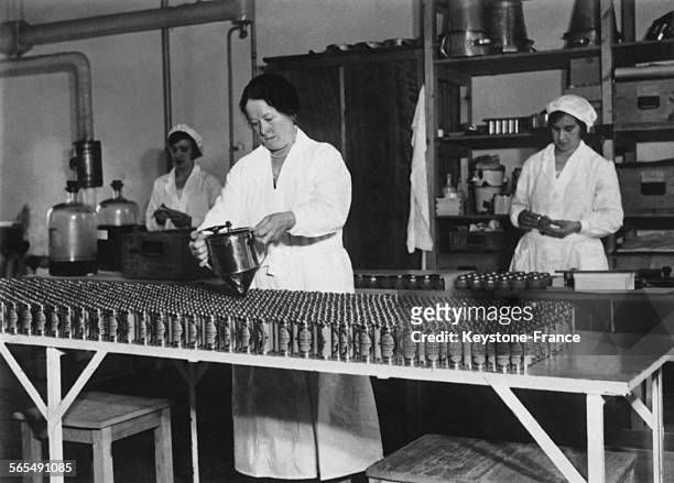Employée remplissant des tubes d'étain d'eau de cologne dans une fabrique à Slough, en Angleterre, Royaume-Uni.