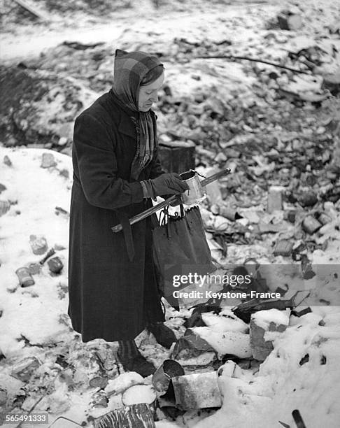 Dans une décharge d'ordures enneigée, une femme affamée fouille dans les boîtes de conserve pour trouver quelques restes à manger, en Allemagne, le...