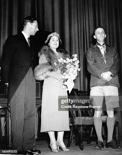 Le Roi George VI et la Reine Elizabeth écoutent des enfants chanter lors de leur visite au 'People's Palace' à Londres au Royaume-Uni.