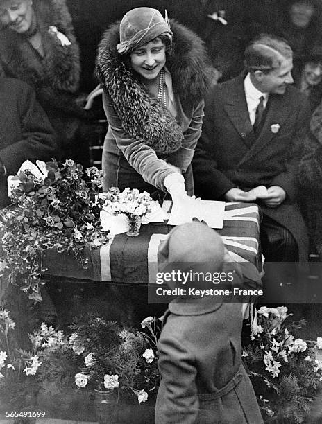 Un petit garçon remet un porte-monnaie en cadeau à la Duchesse d'York venue inaugurer de nouveaux logements ouvriers à Marylebone le 12 décembre 1931...