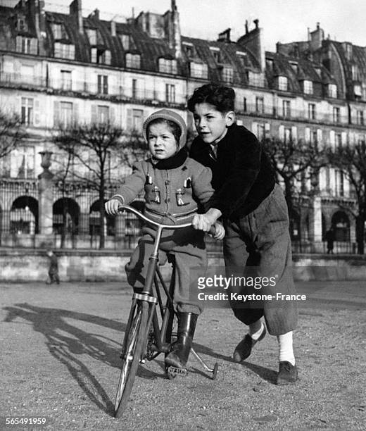 Le grand frère apprend à sa soeur comment monter à bicyclette dans le Jardin des Tuileries ensoleillé, à Paris, France.