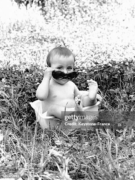 Enfant avec des lunettes de soleil se baigne dans une bassine remplie d'eau froide, à Milan, Italie le 16 juin 1966.