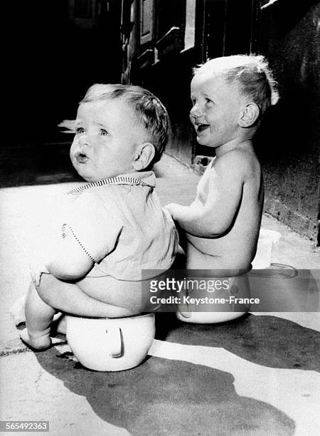 Deux enfants assis sur un pot, en Allemagne le 9 août 1954.