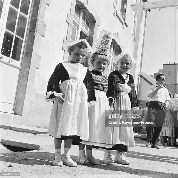 Trois petites filles portant un costume du folklore breton avec la coiffe et les chaussures blanches, à Quiberon, France, en 1957.