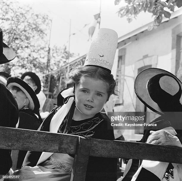 Fillette portant la robe et la coiffe traditionnelles bretonnes, sur une charrette, à Quiberon, France, en 1957.