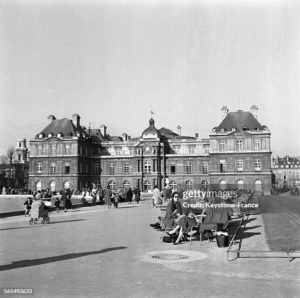 Parisiens profitant des premiers rayons de soleil annonçant le printemps, dans le jardin des Tuileries, à Paris, France, le 2 février 1957.