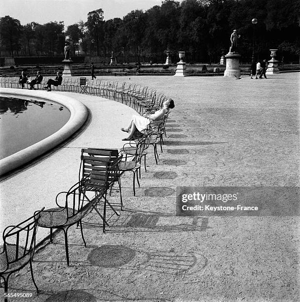 Jeune femme prenant le soleil au bord du bassin du Jardin des Tuileries à Paris, France le 22 septembre 1961.