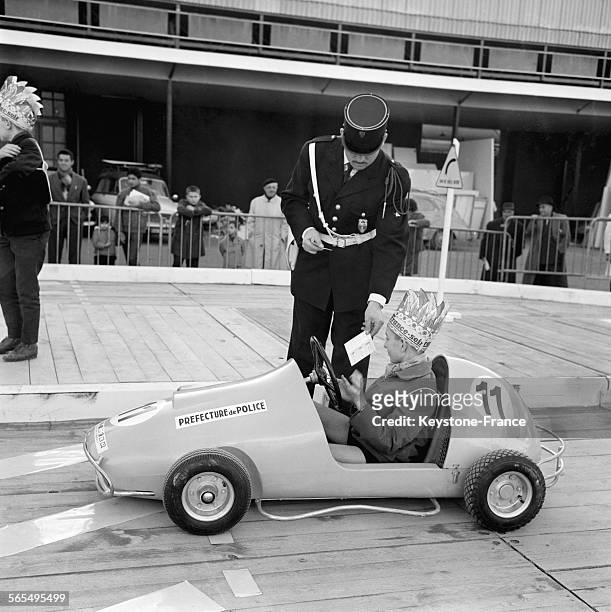 Des enfants conduisent des petites voitures et apprennent le code de la route sous le regard vigilant d'un policier, au Salon de la Porte de...