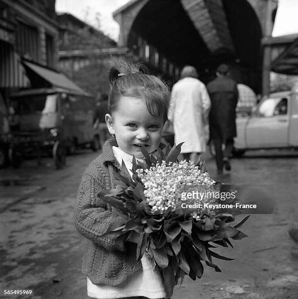 Une petite fille avec un bouquet de muguets dans les mains, à Paris, France le 30 avril 1968.