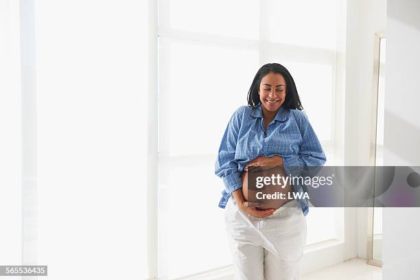 smiling pregnant woman holding stomach - maternity wear 個照片及圖片檔