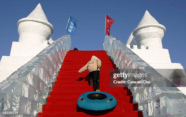 Chinese pupil pull a rubber cushion climbs on a snow slide building at the Sun Island Park, part of the 22nd Harbin International Ice and Snow...