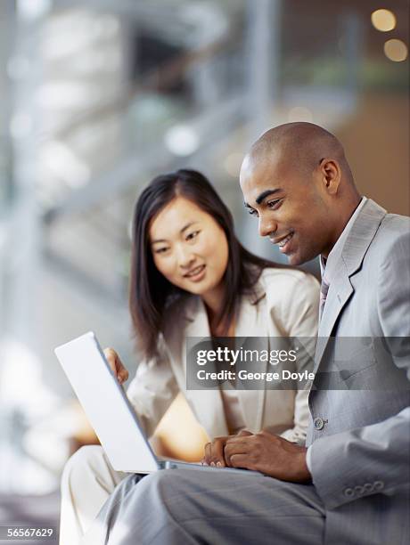 side profile of a businessman and a businesswoman using a laptop - profile laptop sitting stock pictures, royalty-free photos & images