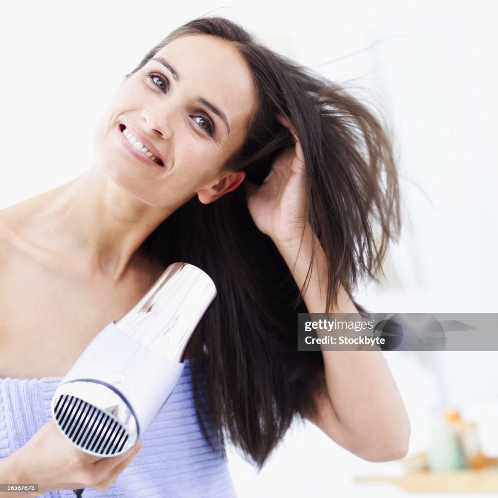 Young woman drying her hair with a hair dryer