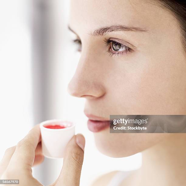 side profile of a young woman holding a cup of mouthwash - mouthwash stock-fotos und bilder