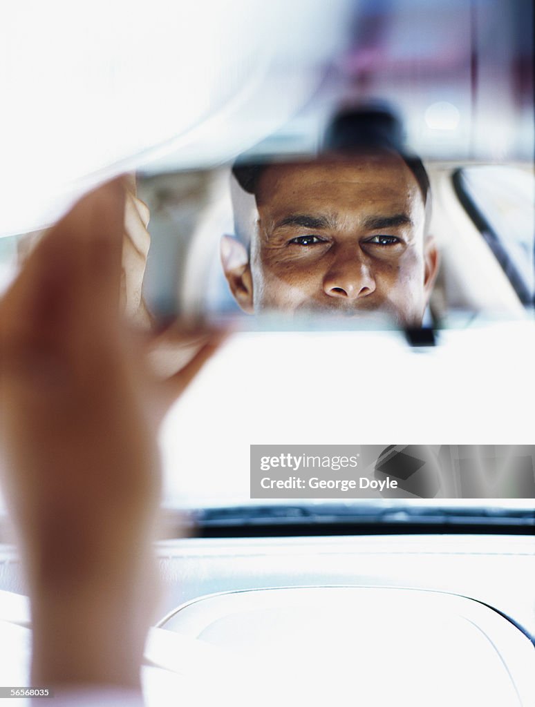 Businessman looking in a rear view mirror in a car