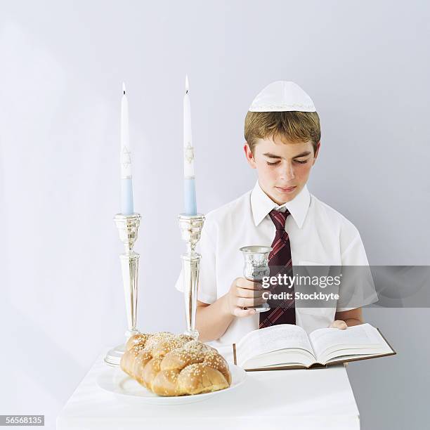 jewish boy reading the talmud with a kiddush cup in hand - kiddush cup fotografías e imágenes de stock