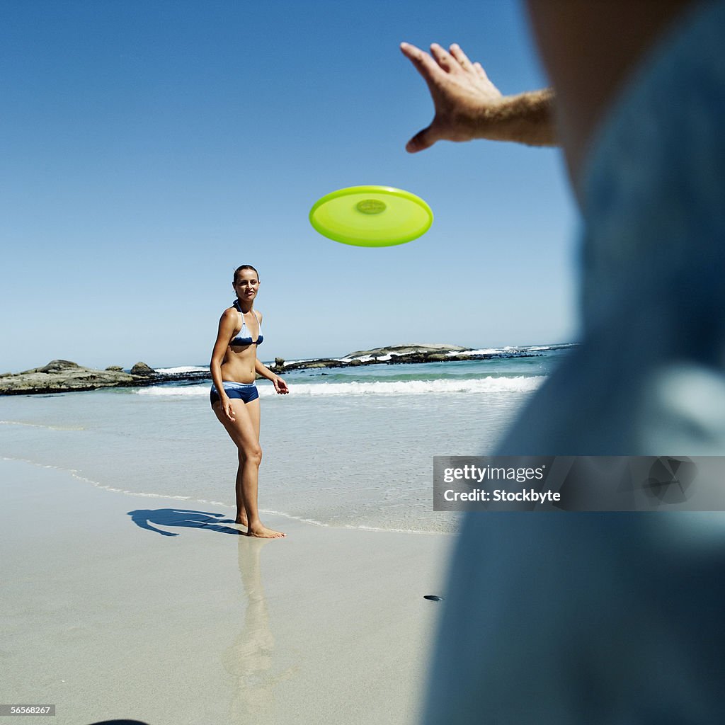 Young couple playing with a flying disc on the beach