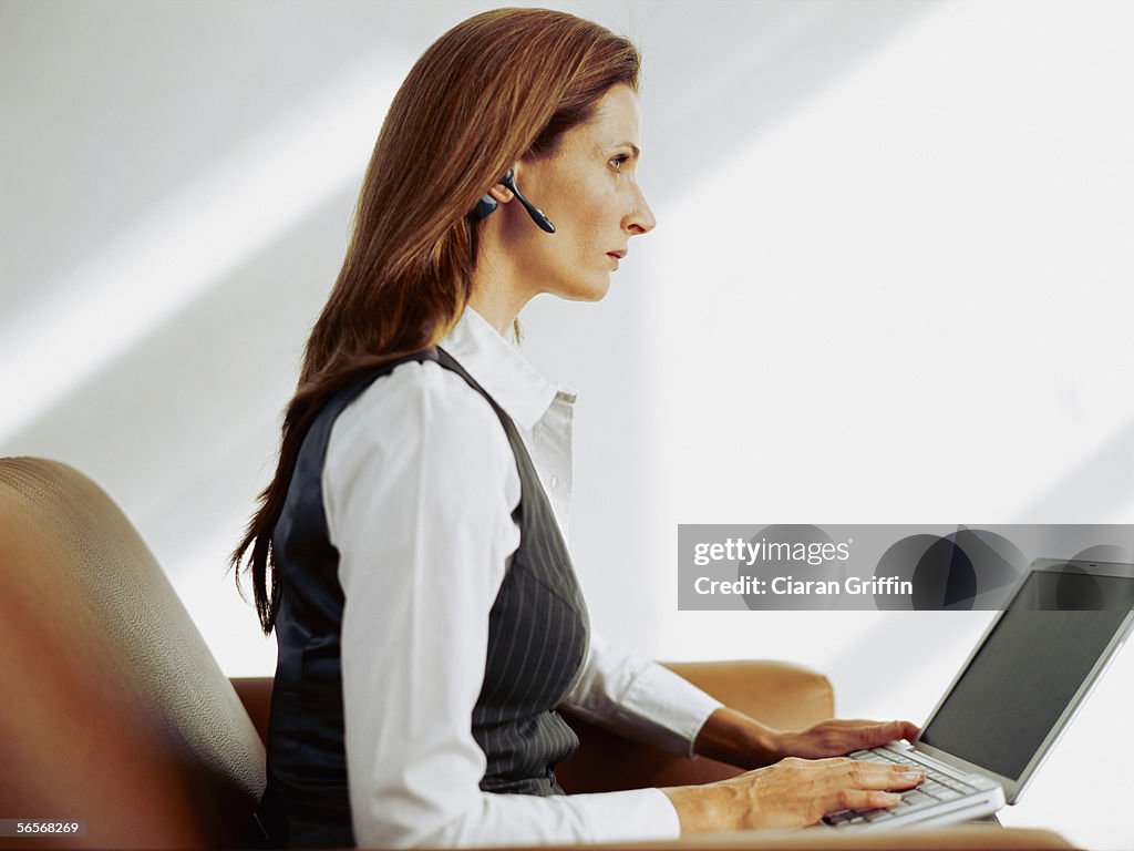 Side profile of a businesswoman sitting on a couch and using a laptop