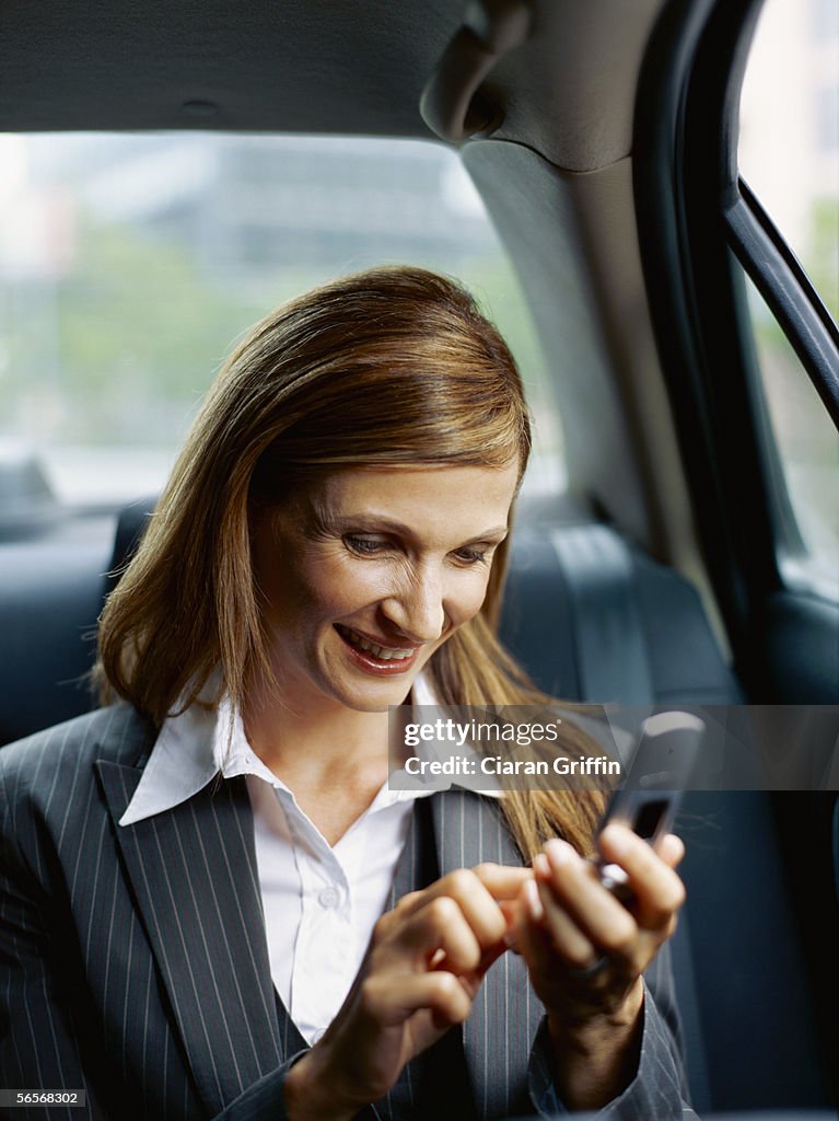 Businesswoman using a mobile phone in a car
