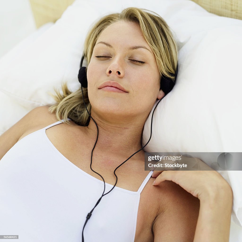 Close-up of a young woman lying on the bed listening to music