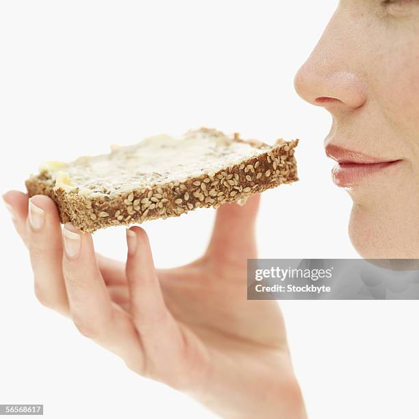 side profile of a young woman holding a piece of sesame seed toast - brot mund stock-fotos und bilder