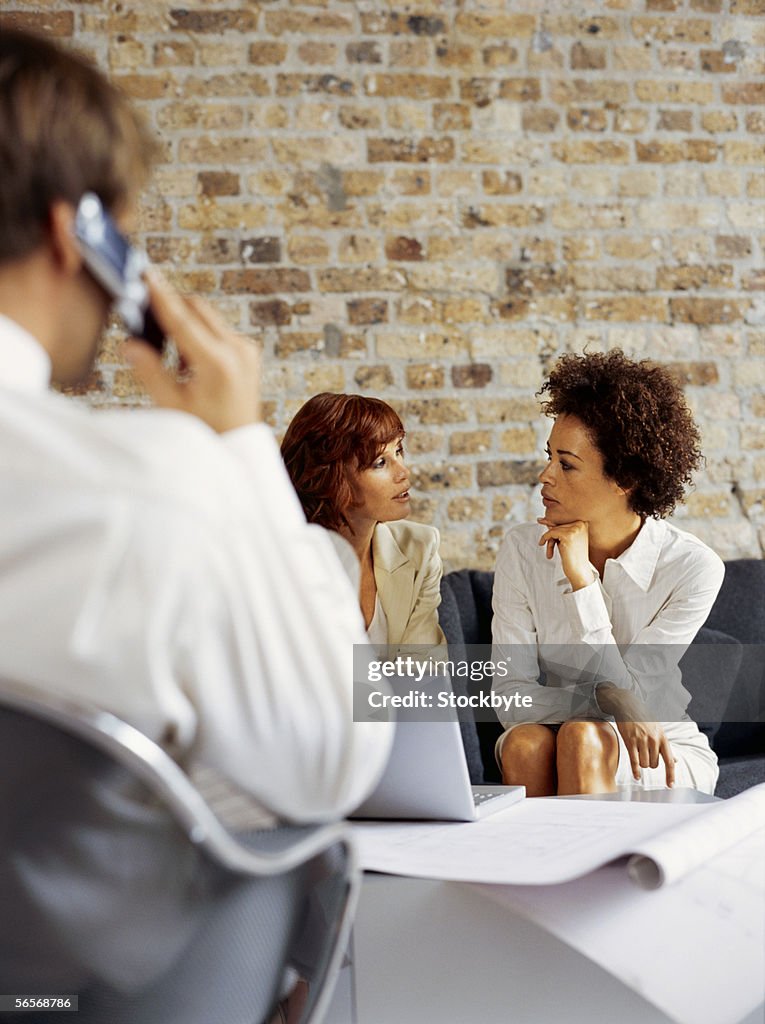 Businessman and two businesswomen sitting in a conference room