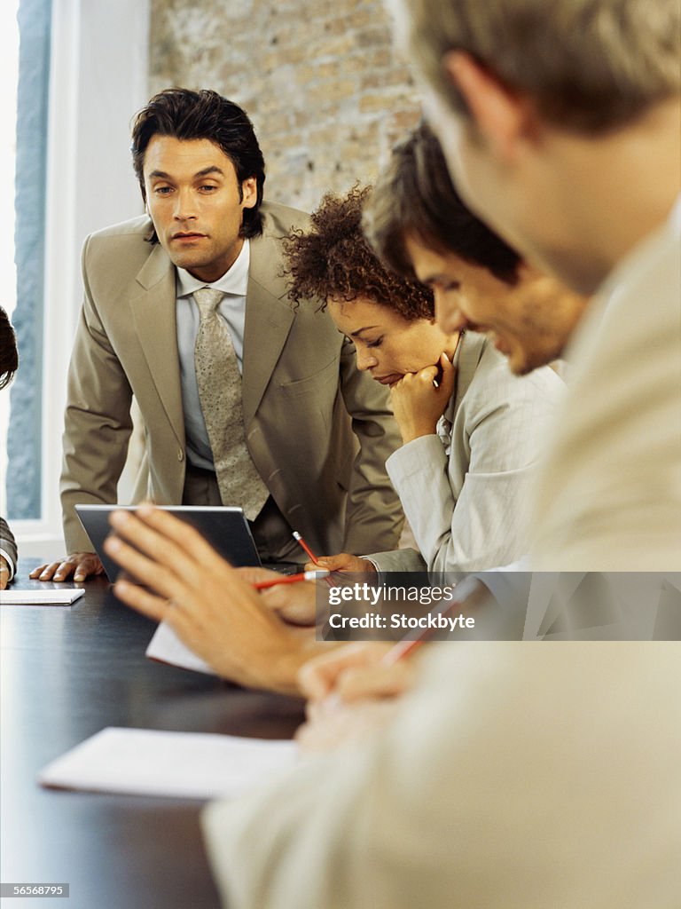 Three businessmen and a businesswoman discussing in a meeting