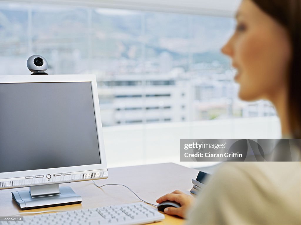 Businesswoman sitting in front of a video conference camera in an office