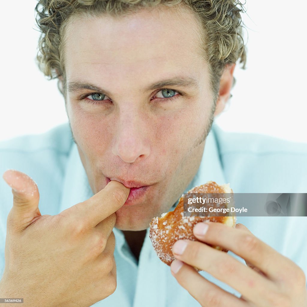 Close-up of a young man licking the filling of a donut