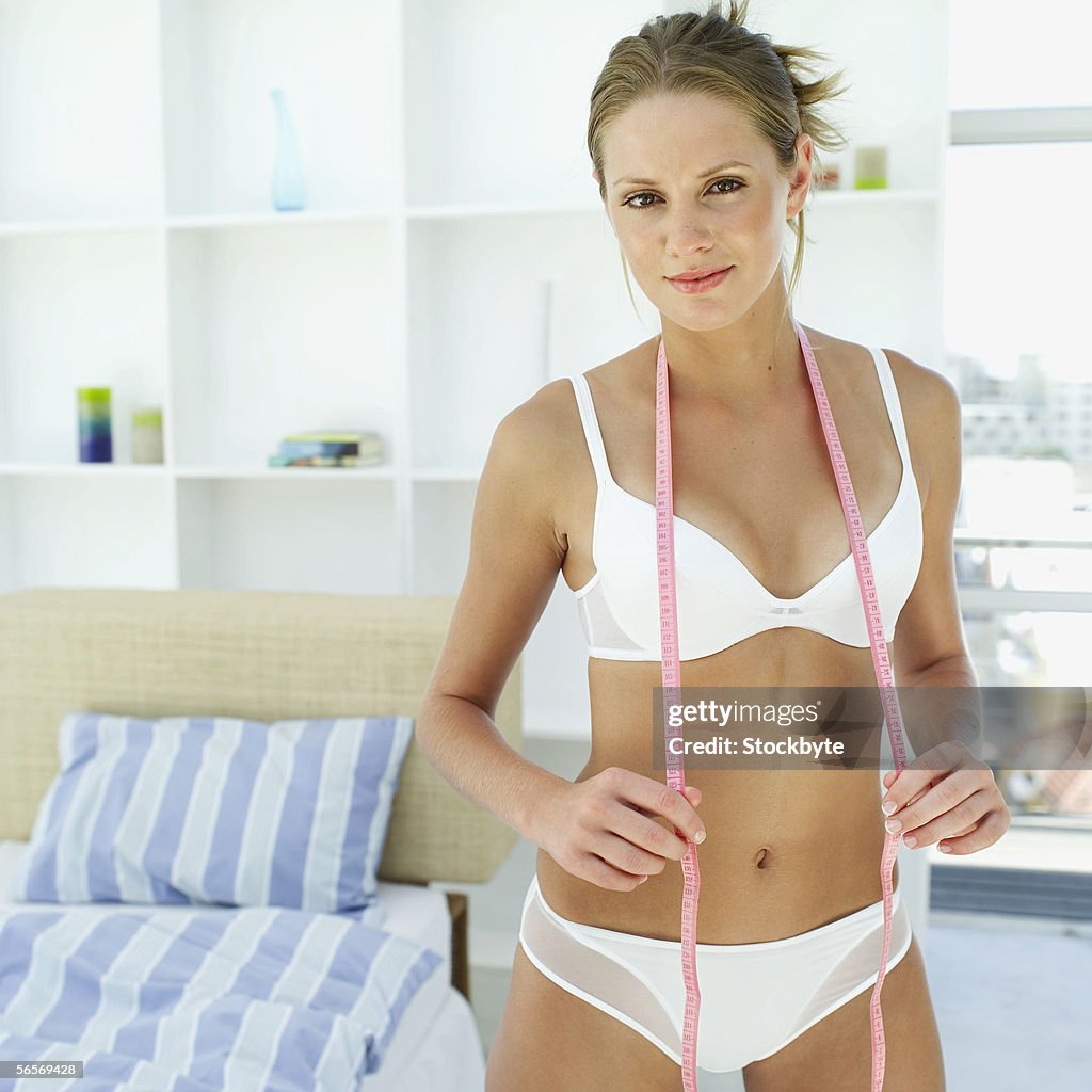 Portrait of a young woman holding a measuring tape around her neck