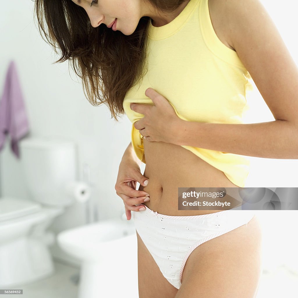 Close-up of a young woman pinching her stomach