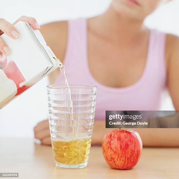 close-up of a young woman's hand pouring juice from a carton into a glass - juice carton 個照片及圖片檔