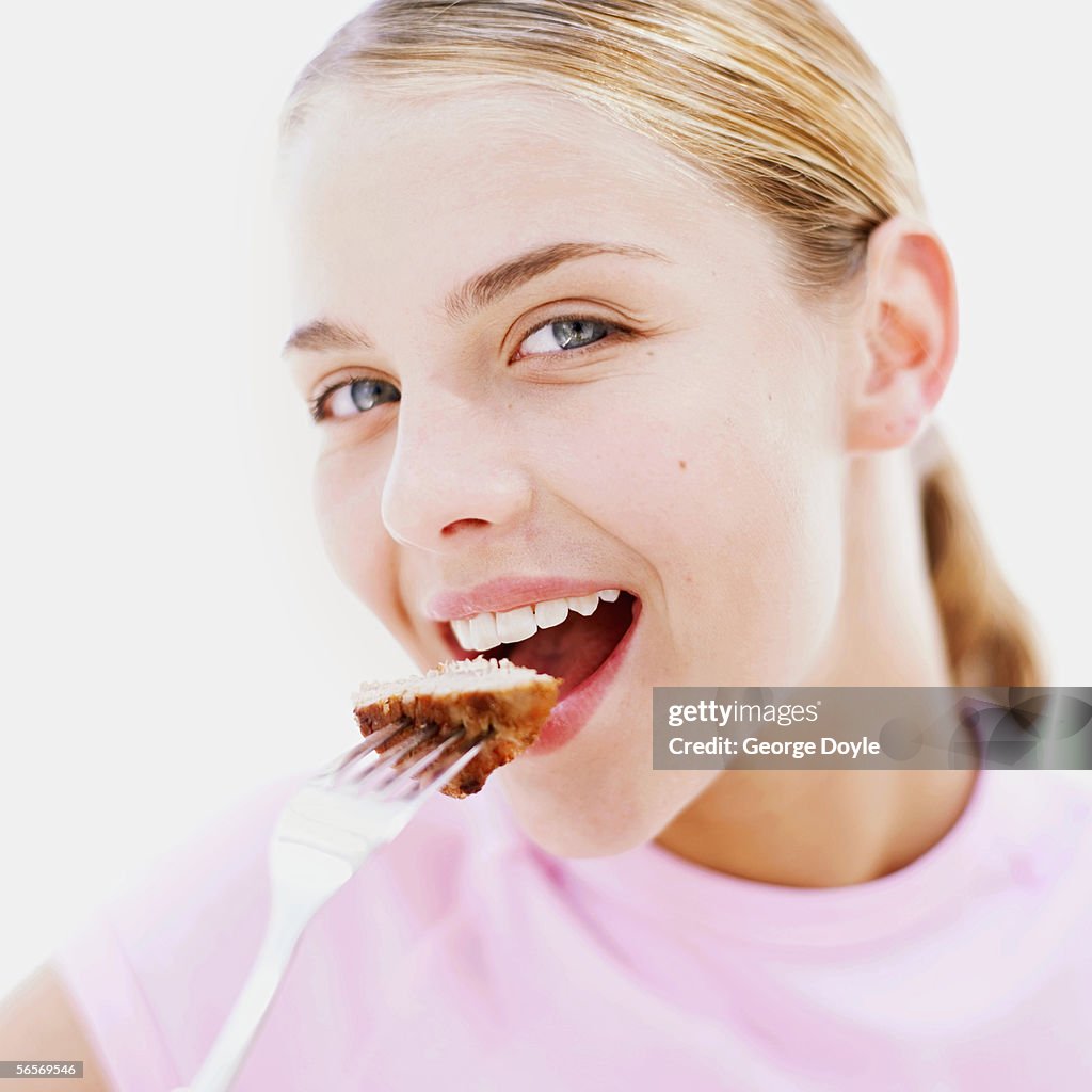 Close-up of a teenage girl eating a piece of steak
