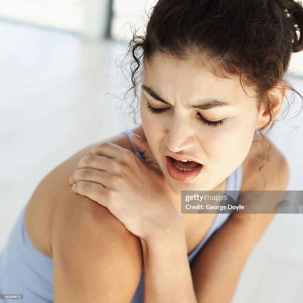 High angle view of a young woman holding her shoulder in pain