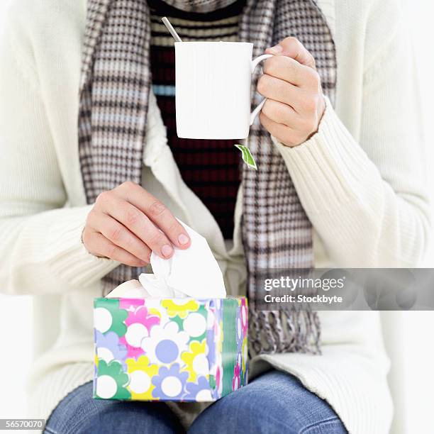 close-up of a woman holding a mug and a box of tissues - papiertaschentuch stock-fotos und bilder