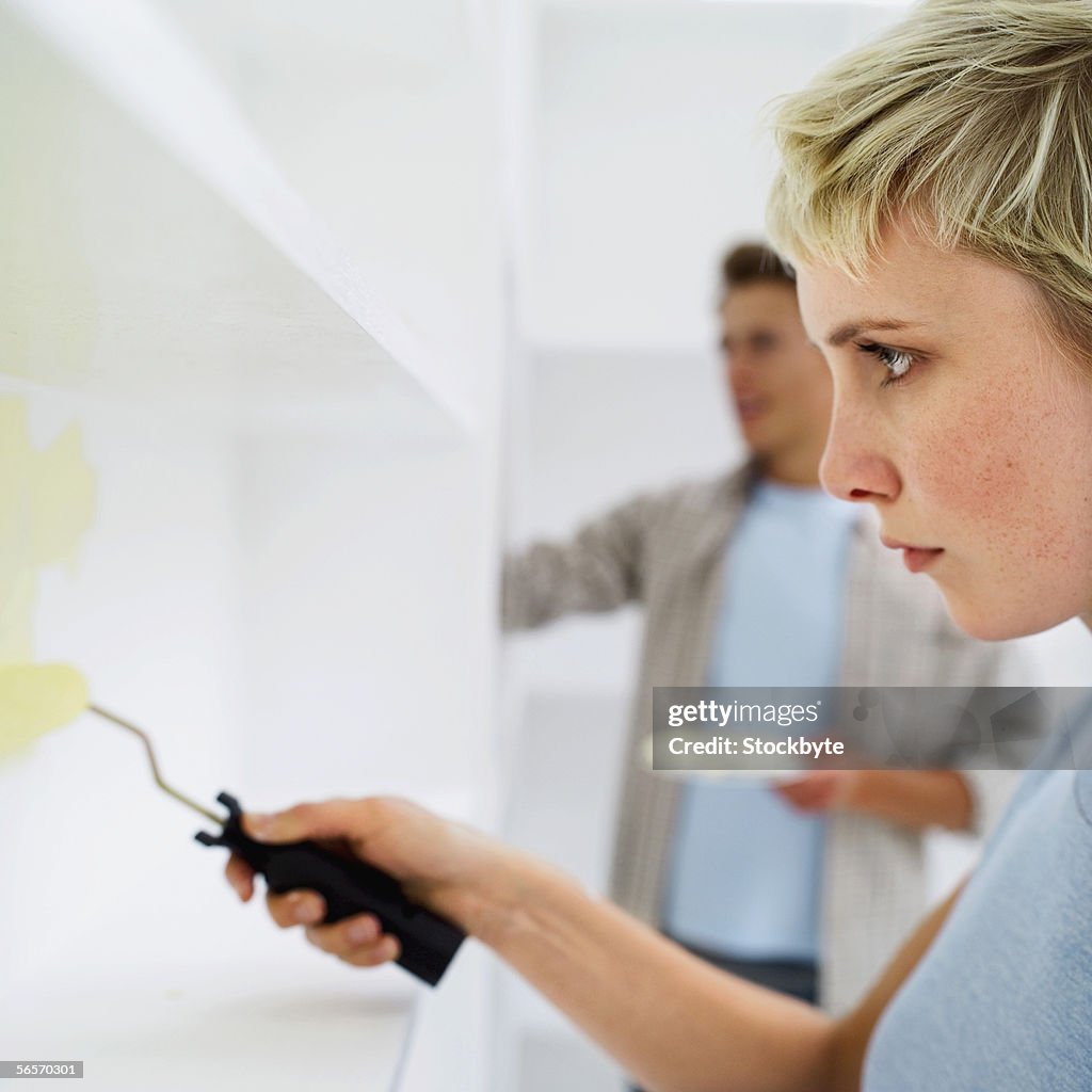 Close-up of a young couple painting shelves