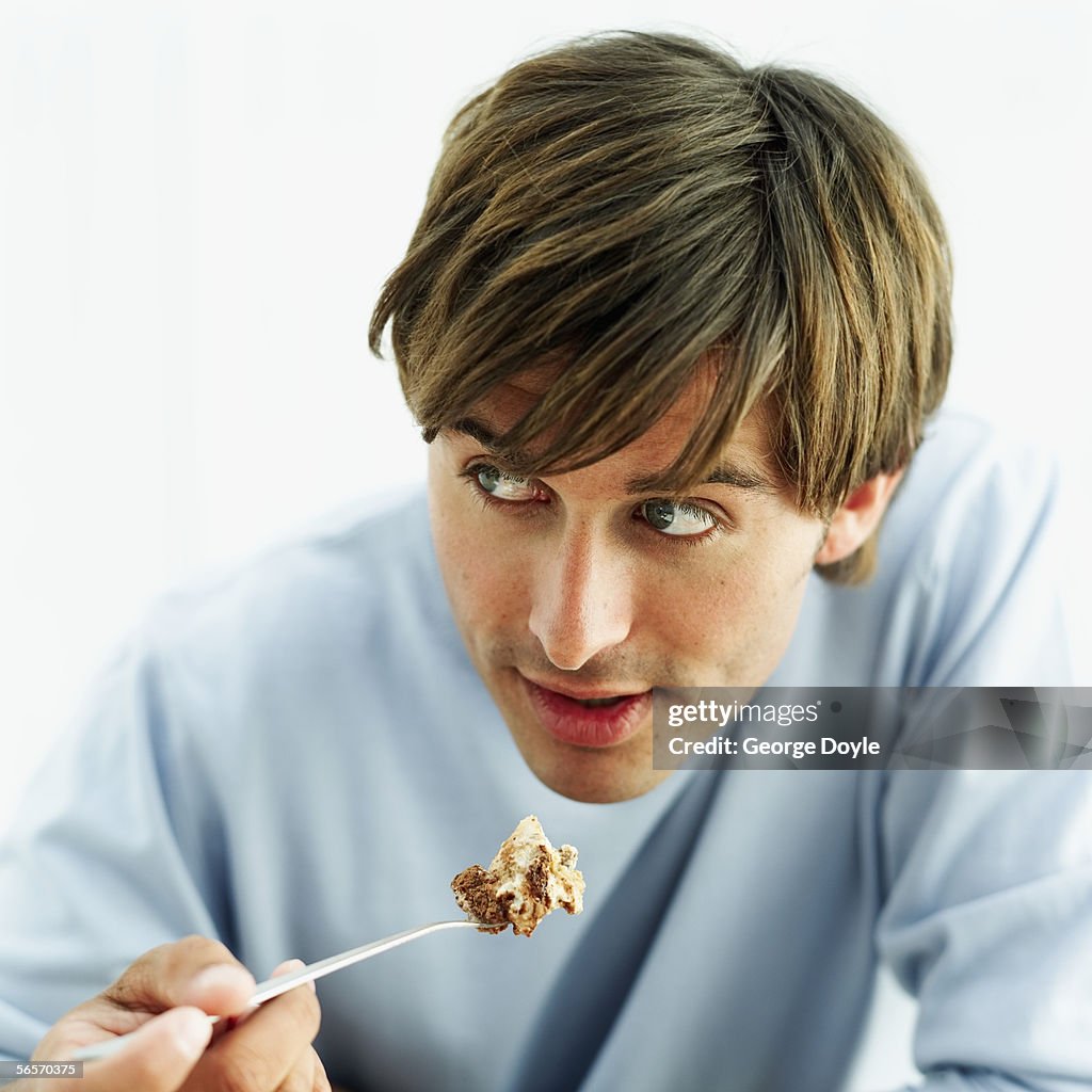 Young man holding a portion of tiramisu with a spoon