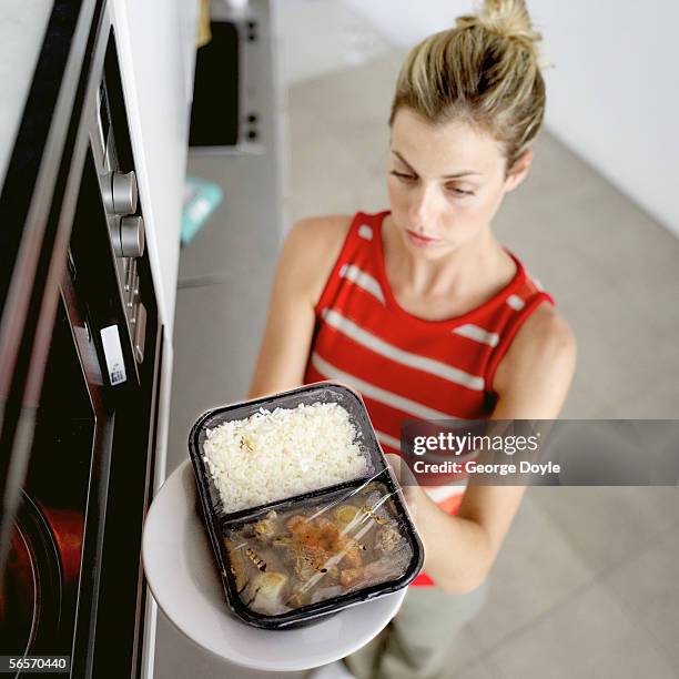 young woman placing food in the microwave - tv dinner stock pictures, royalty-free photos & images