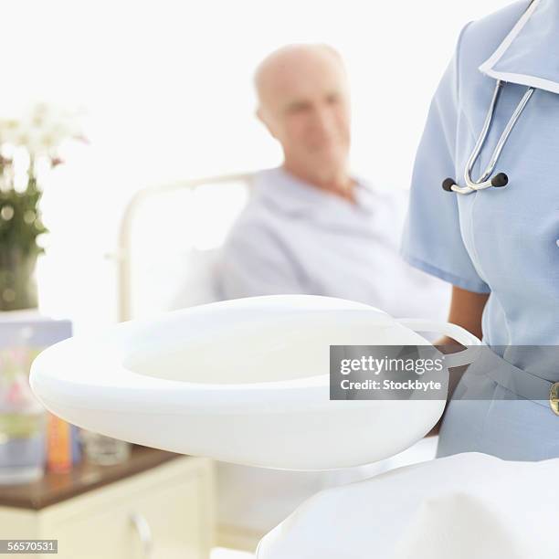 close-up of a nurse holding a bed pan - hospital bedpan stock pictures, royalty-free photos & images