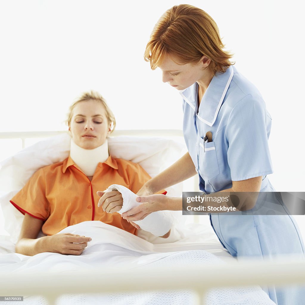 Female nurse tending to a young woman with a neck brace and an arm cast