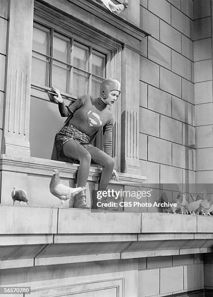 American actress and comedian Lucille Ball stands awkwardly perched on a ledge in a makeshift Superman outfit complete with underpants and football...