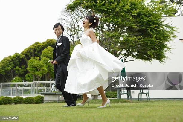 bride and groom running on lawn - bride running stock-fotos und bilder