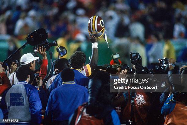 Washington Redskins' Doug Williams holds up his helmet after helping his team win the Super Bowl XXII against the Denver Broncos at Jack Murphy...