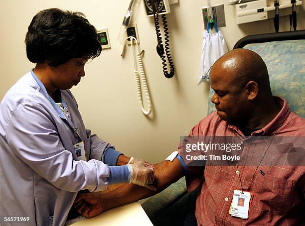Evanston Hospital employee Corey Dale has his blood drawn for screening by Evanston Hospital Lab Services Phlebotomist Doris McGuire at Evanston...