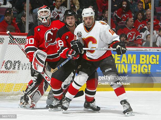 Tony Amonte of the Calgary Flames moves into position against goaltender Martin Brodeur and Brian Rafalski of the New Jersey Devils on December 7,...
