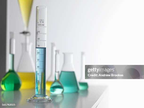 laboratory glassware on lab bench with a graduated measuring cylinder in foreground - mätglas bildbanksfoton och bilder