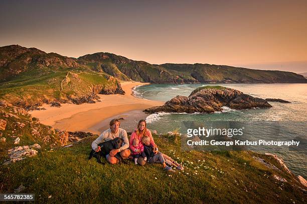 portrait of family sitting on hillside, murder hole beach, melmor head, ireland - irish family stock-fotos und bilder